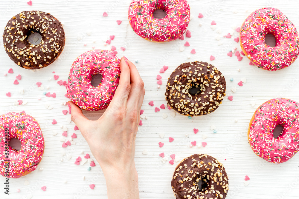 Hand holding glazed donut swith sprinkles, above view