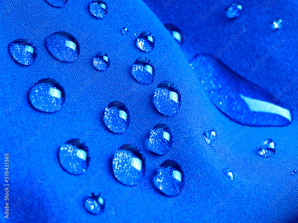 Blue waterproof fabric with raindrops close up