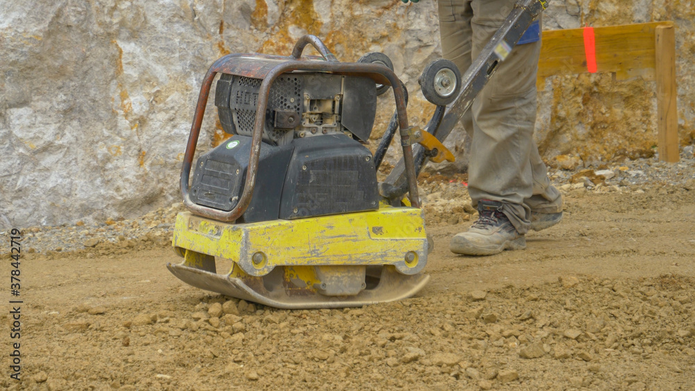 CLOSE UP Man uses manual levelling machine to prepare ground for mortar pouring