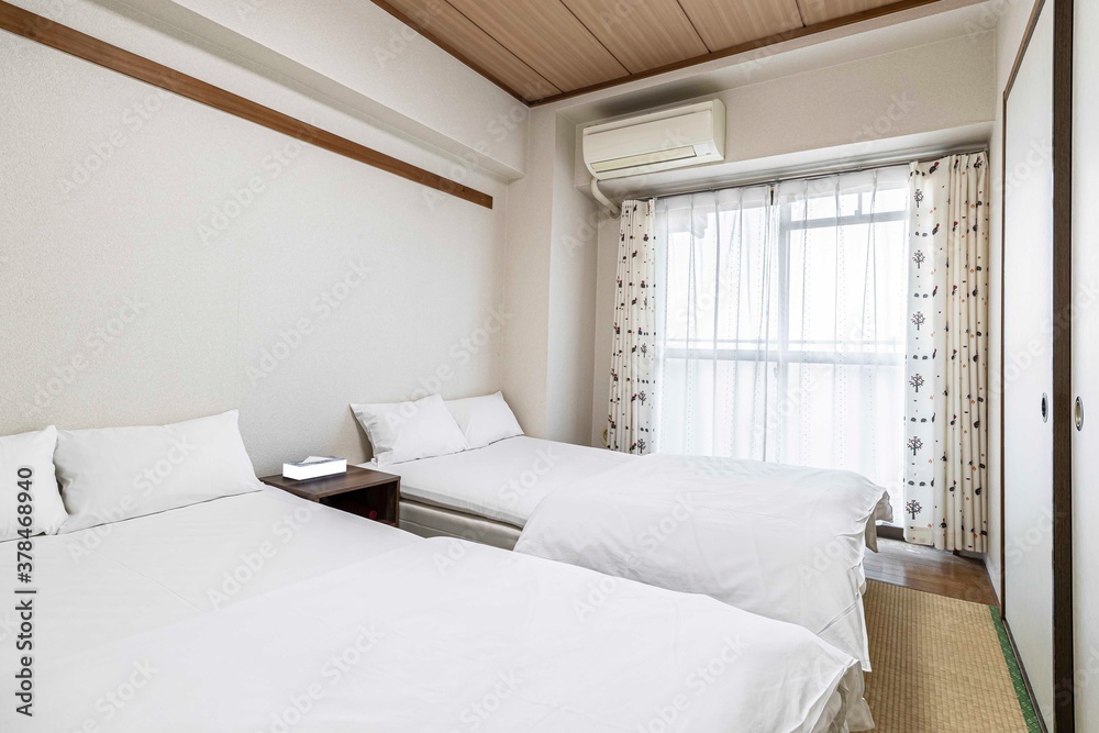 Twin beds and white blankets in a small white bedroom at a Japanese-style house