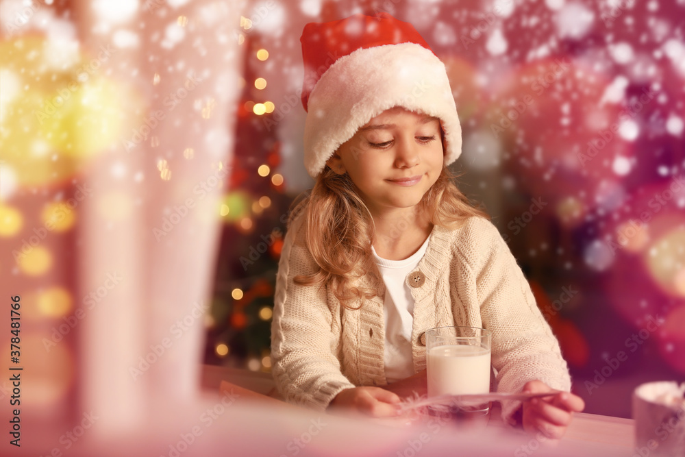 Cute little girl writing letter to Santa Claus on Christmas eve at home