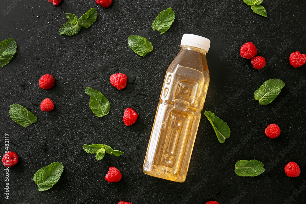 Bottle of fresh ice tea, mint and raspberry on dark background