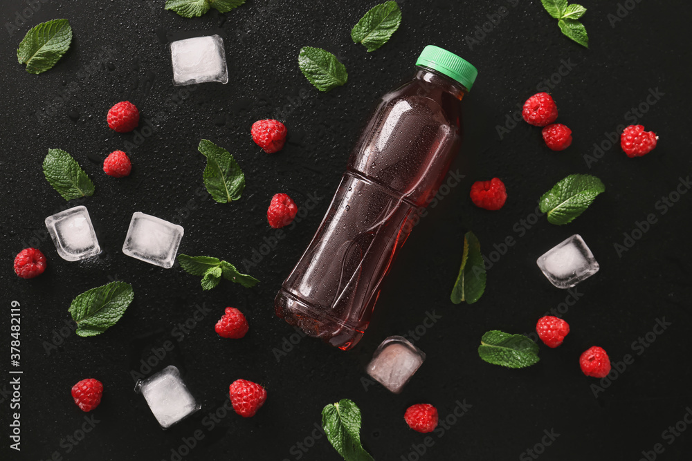 Bottle of fresh  tea, mint, ice cubes and raspberry on dark background