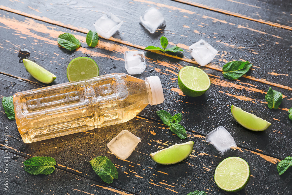 Bottle of fresh ice tea, mint and lemon on dark wooden background