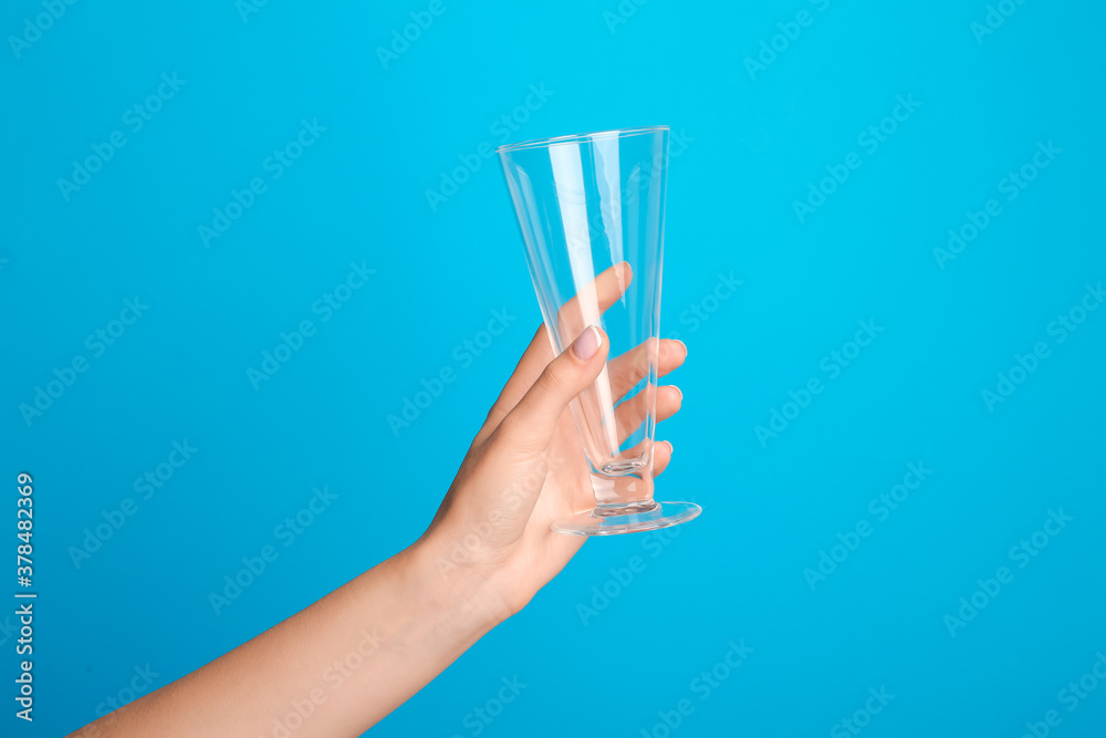 Hand with empty glass on color background