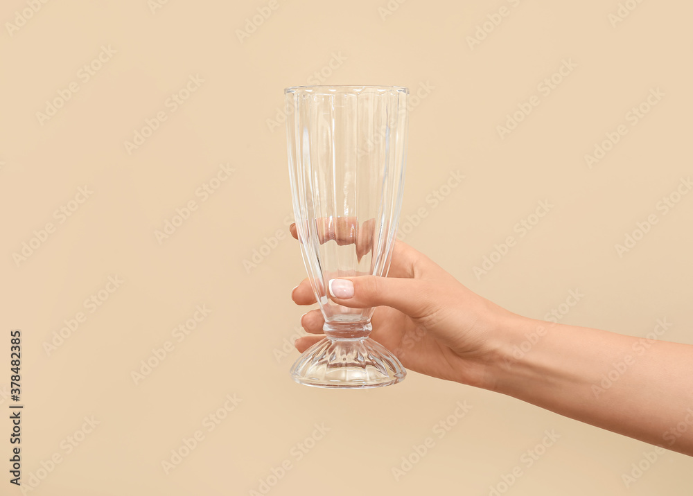 Hand with empty glass on color background