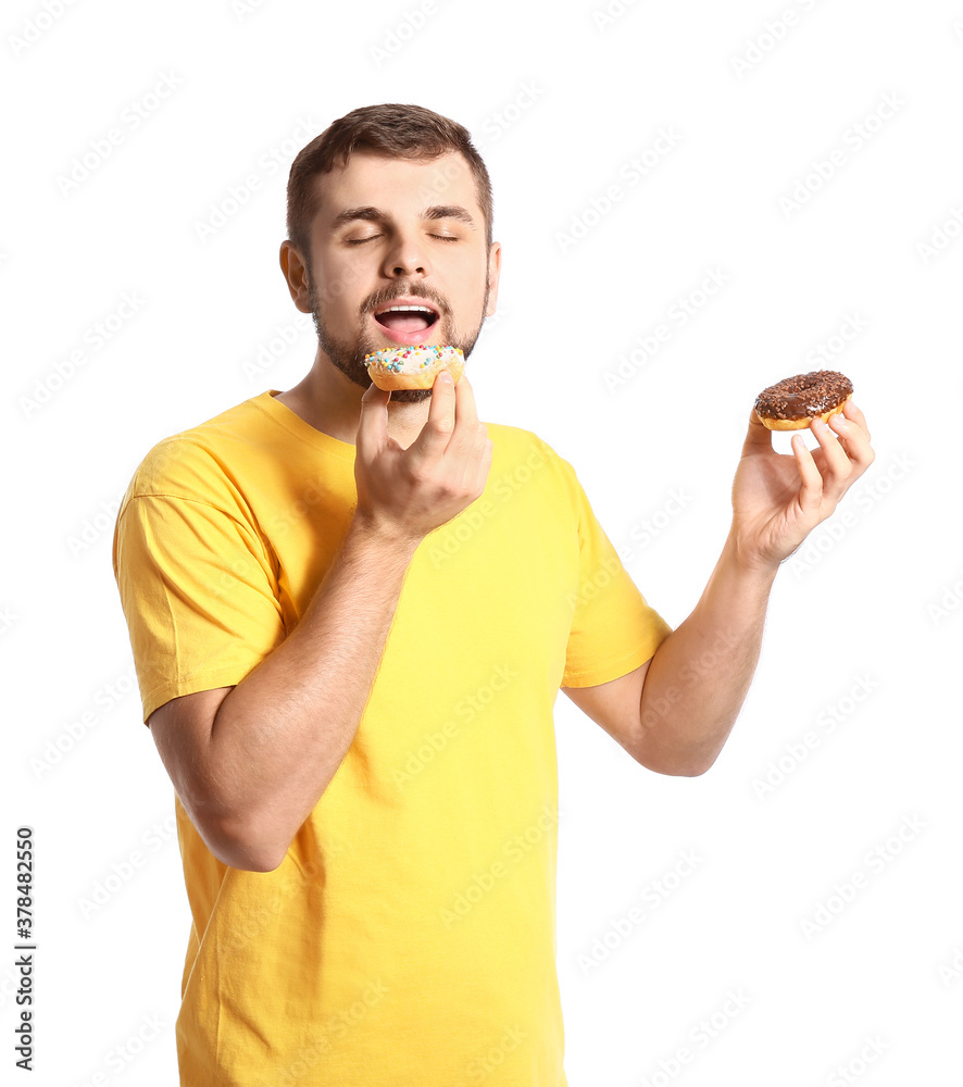 Handsome young man with sweet donuts on white background