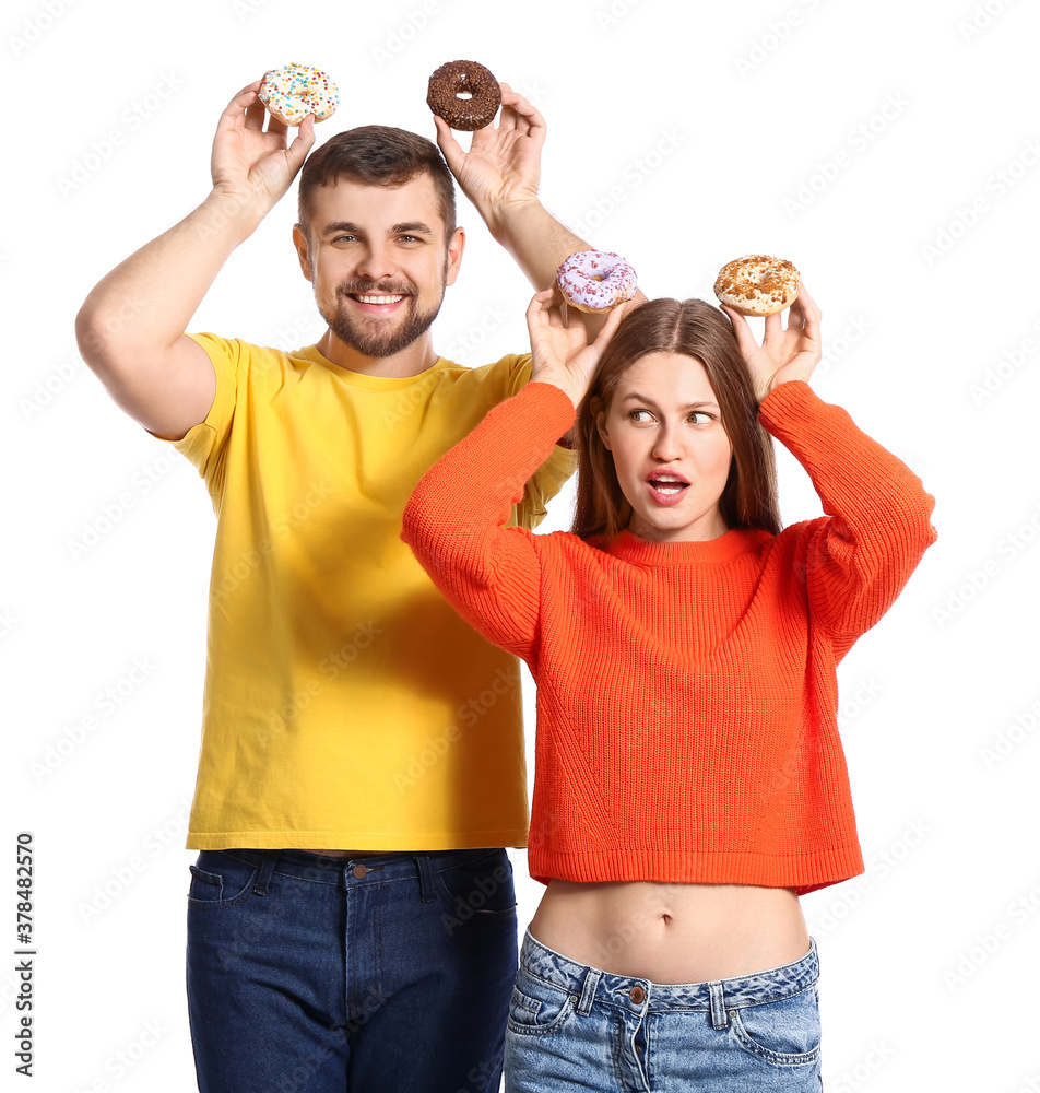 Young couple with sweet donuts on white background