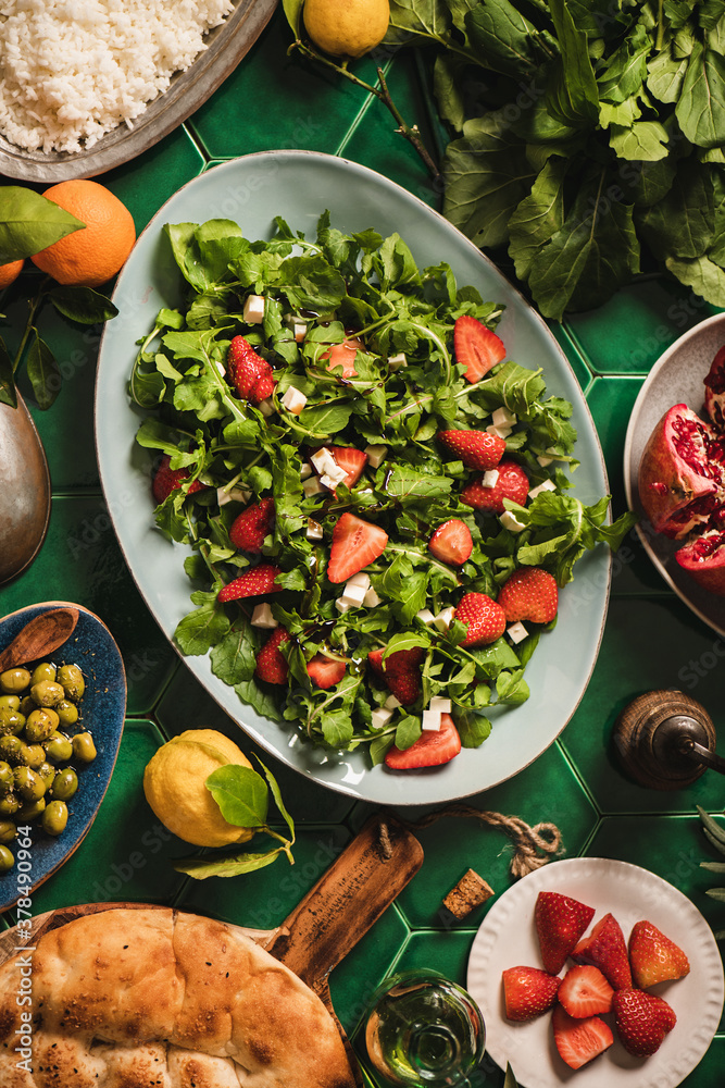 Turkish Mediterranean dinner table setting. Flat-lay of arugula, soft cheese and strawberry salad, r