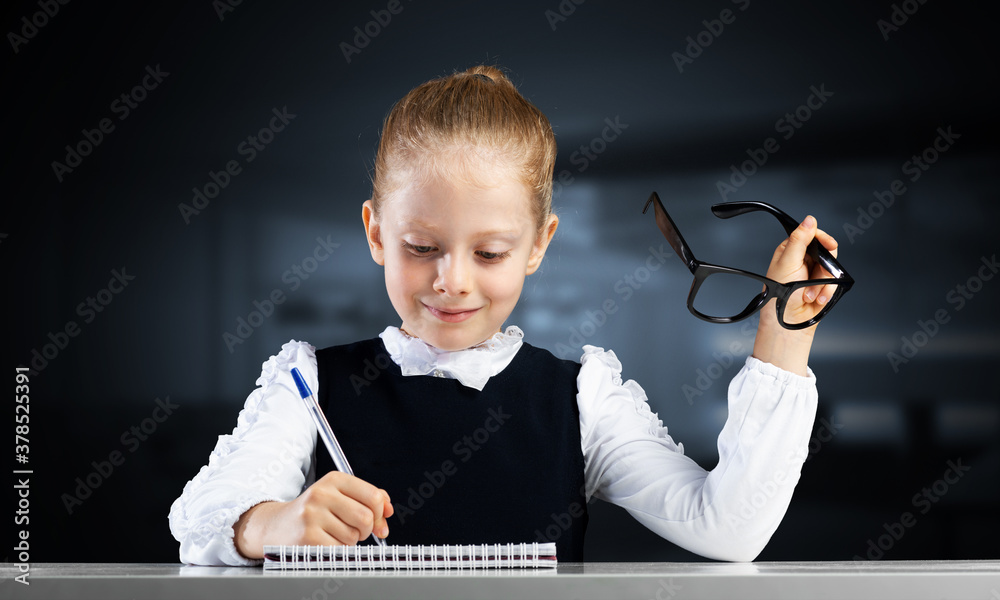 Smiling little girl in schoolwear doing homework