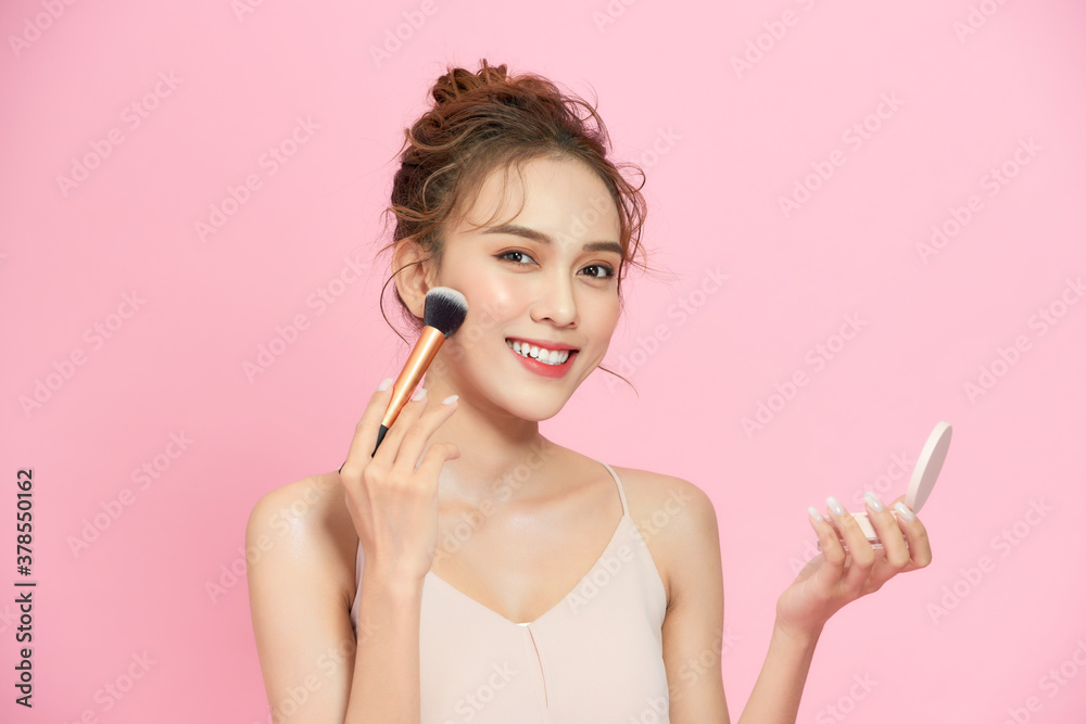 Closeup portrait of beautiful happy young girl with perfect skin is holding makeup brush in hand. Is