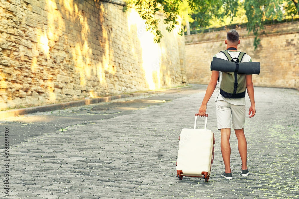 Male tourist with luggage on city street