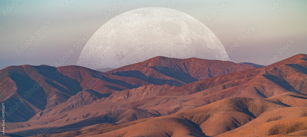 Giant moon in the evening sky over the mountains. Elements of this image furnished by NASA.