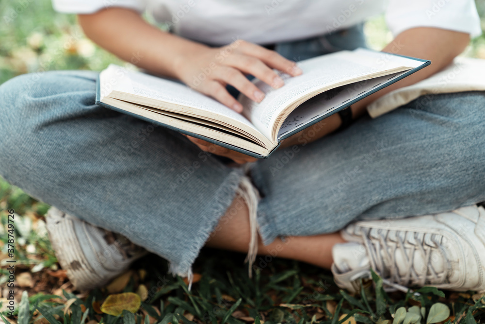 Close up University student with a book at park.