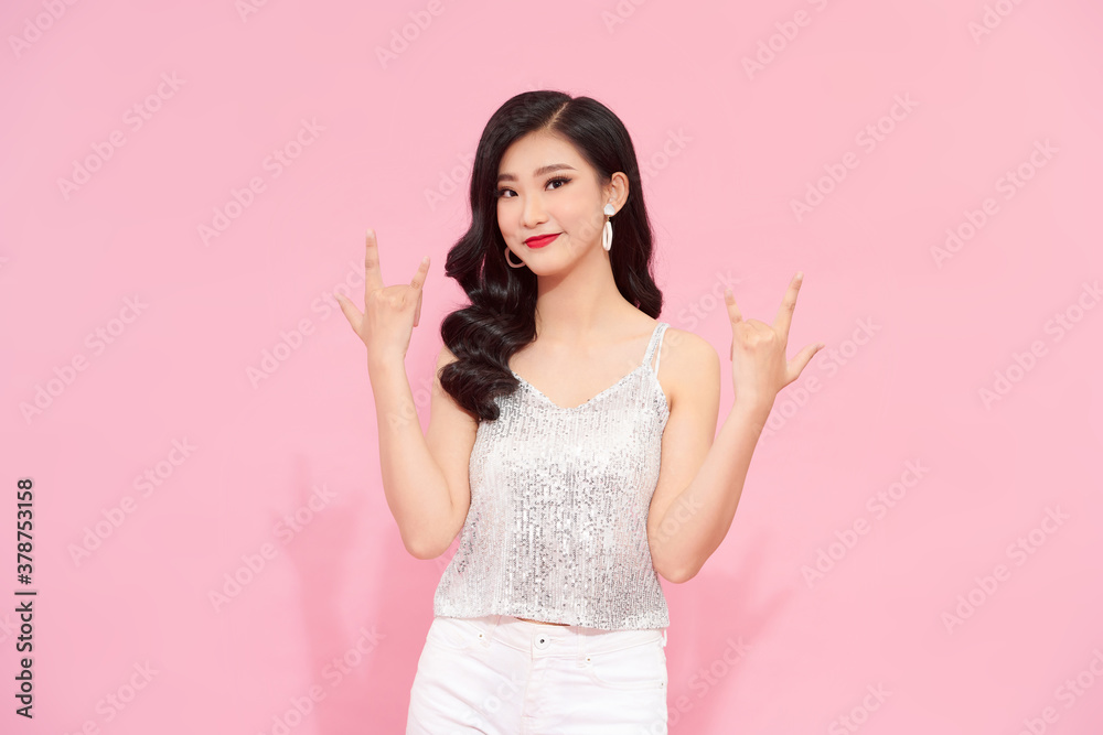 cheerful beautiful woman wearing bright clothes and makeup standing over pink background