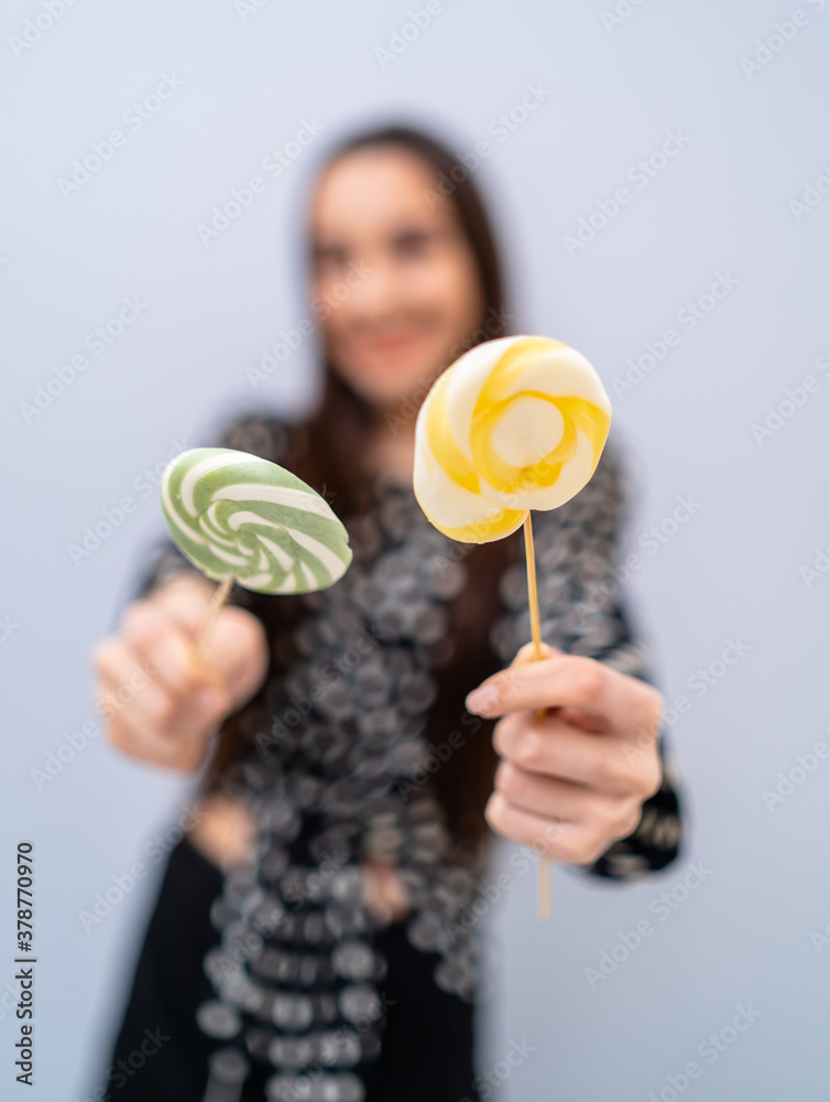 Fashion model girl with round candy in hands. Beautiful smiling young woman. Cropped photo.