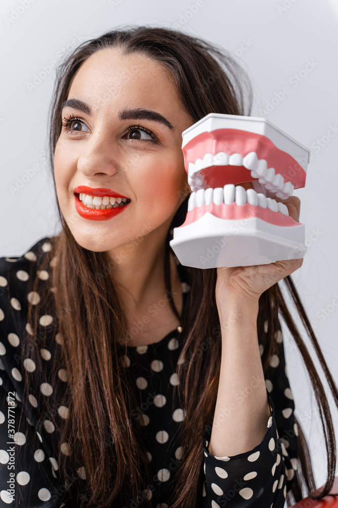 Woman holding educational model of oral cavity with teeth on white background. Funny emotions and ex