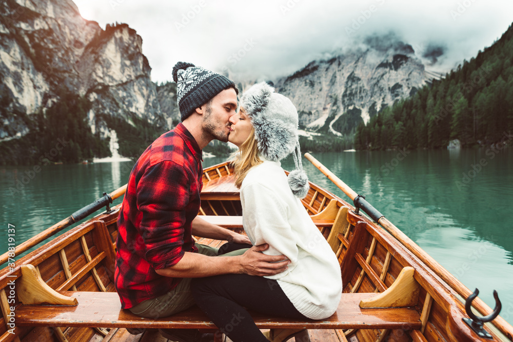 Romantic kiss of a couple of adults visiting an alpine lake at Braies Italy. Tourist in love spendin