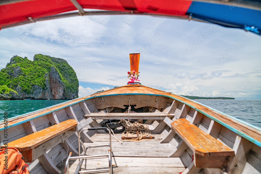 Traditional wooden longtail boat against steep limestone hills in phi phi island krabi province Thai