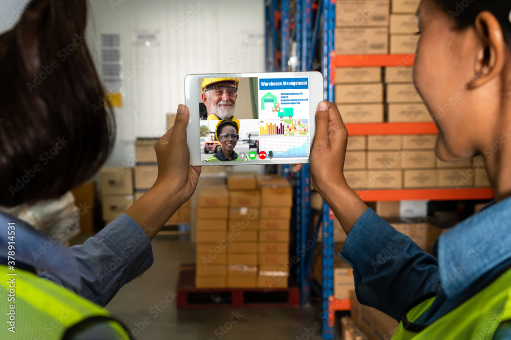 Warehouse staff talking on video call at computer screen in storage warehouse . Online software tech