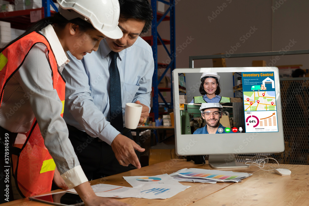 Warehouse staff talking on video call at computer screen in storage warehouse . Online software tech