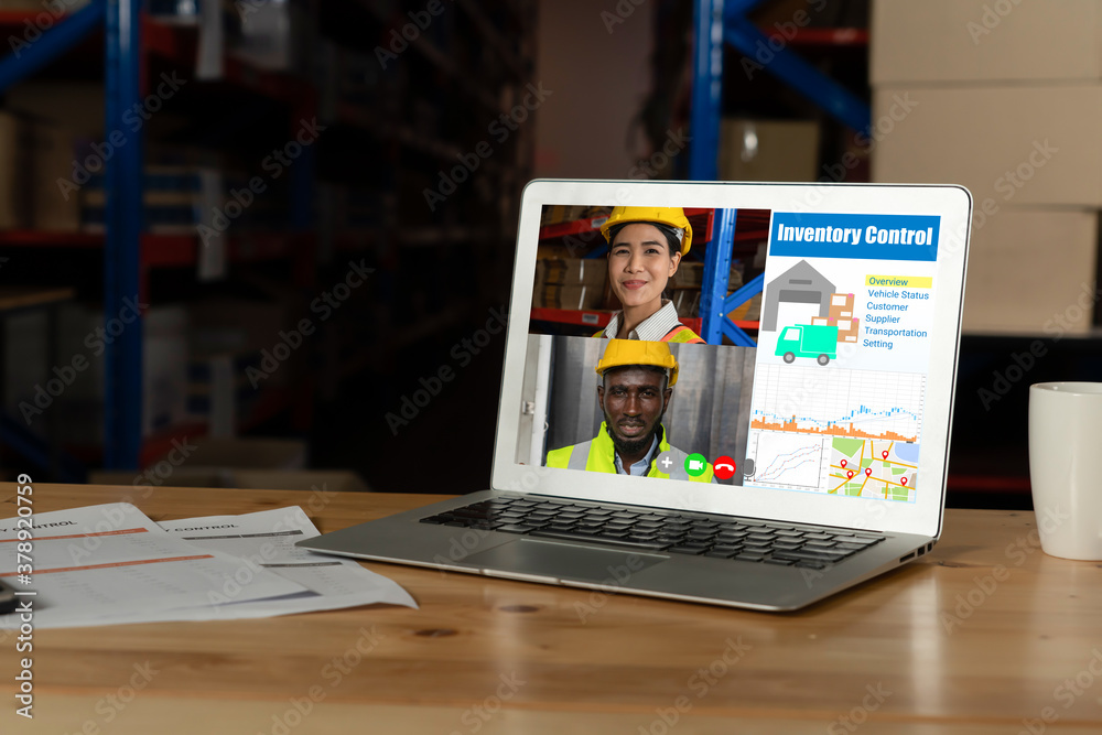 Warehouse staff talking on video call at computer screen in storage warehouse . Online software tech