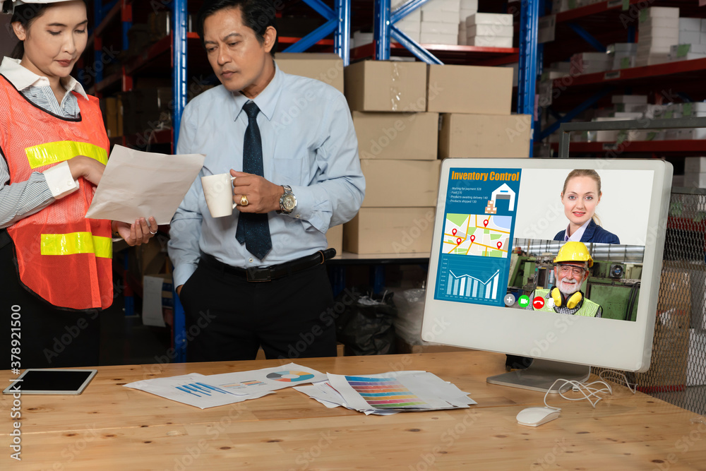 Warehouse staff talking on video call at computer screen in storage warehouse . Online software tech