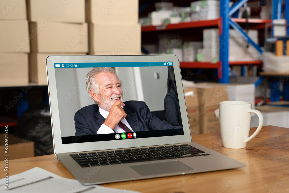 Warehouse staff talking on video call at computer screen in storage warehouse . Online software tech