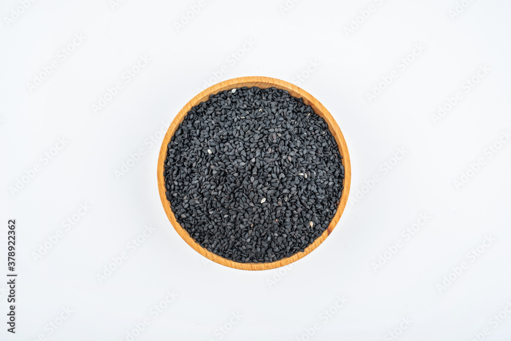 Black sesame seeds in a saucer on white background