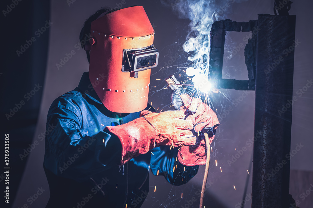 Metal welding steel works using electric arc welding machine to weld steel at factory. Metalwork man