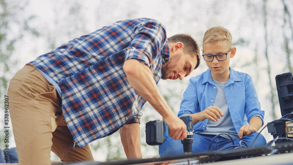 Father and Son Installing Solar Panels to a Metal Basis with a Drill. They Work on a House Roof on a