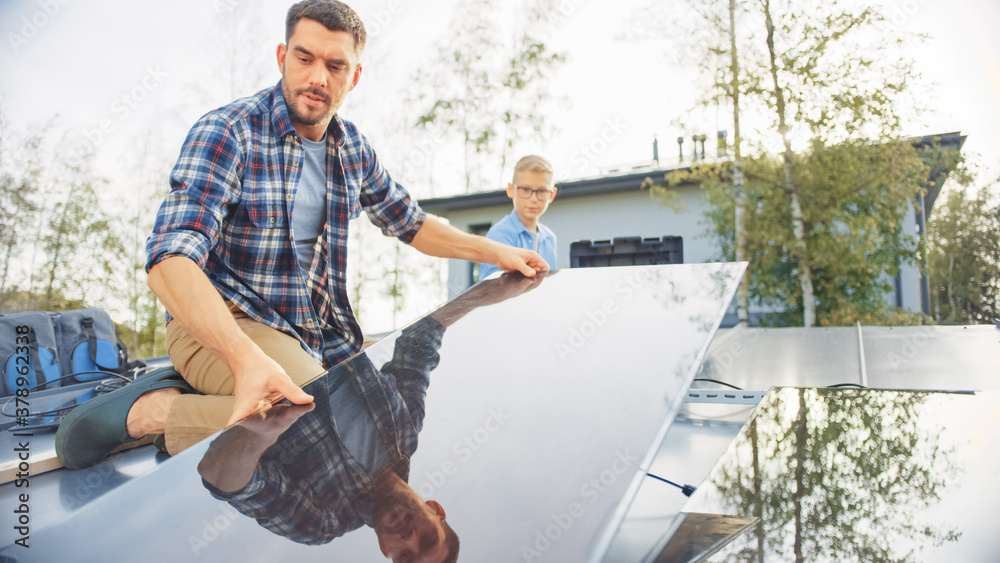 Father and Son Installing Solar Panels to a Metal Basis with a Drill. They Work on a House Roof on a