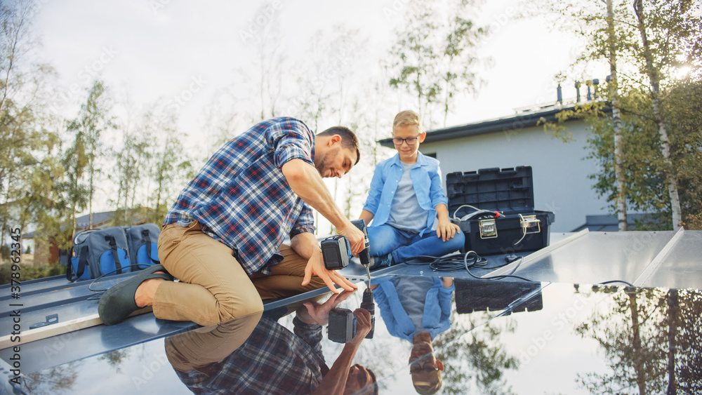 Father and Son Installing Solar Panels to a Metal Basis with a Drill. They Work on a House Roof on a