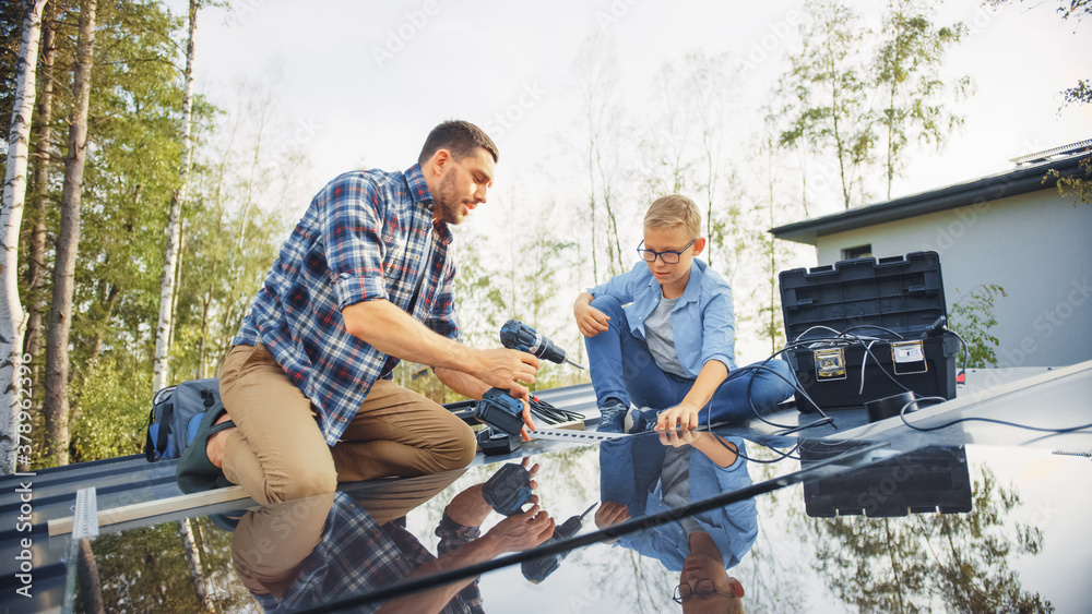 Father and Son Installing Solar Panels to a Metal Basis with a Drill. They Work on a House Roof on a