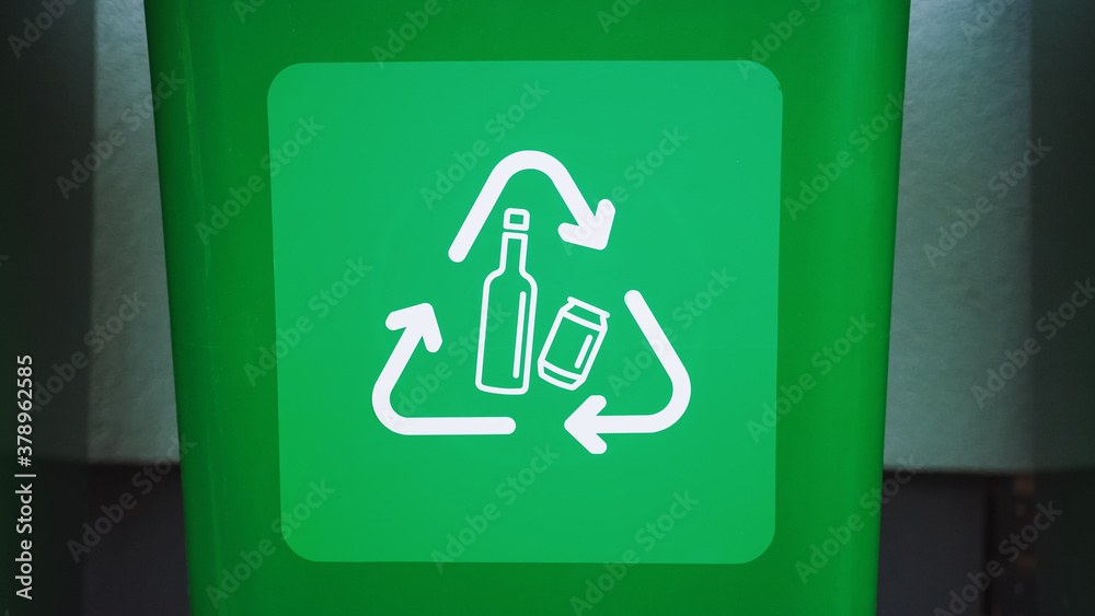 Close-up Shot of a Green colored, plastic garbage bin, with bottle recycle logos on front. Concept o