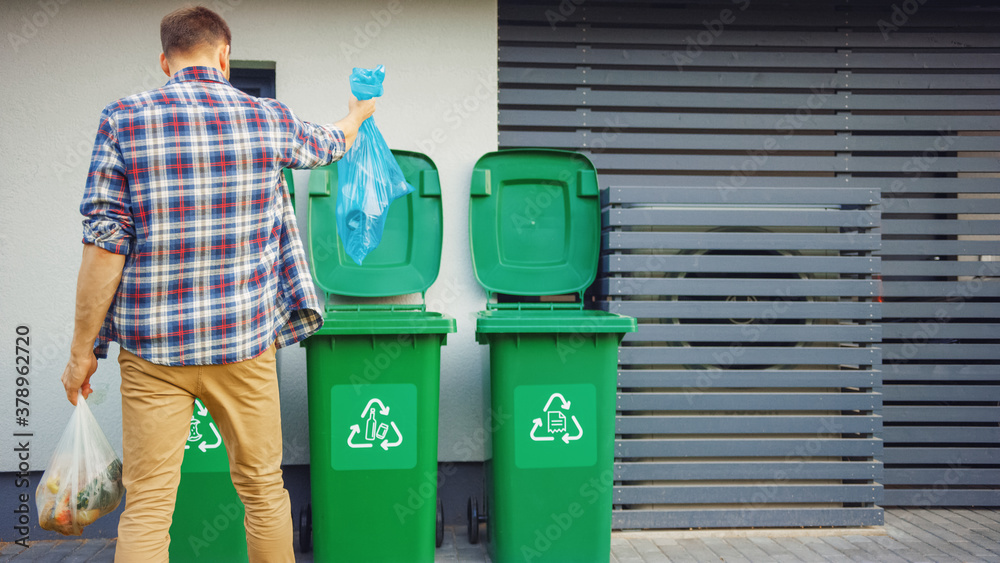 Caucasian Man is Throwing Away Two Plastic Bags of Trash next to His House. One Garbage Bag is Sorte