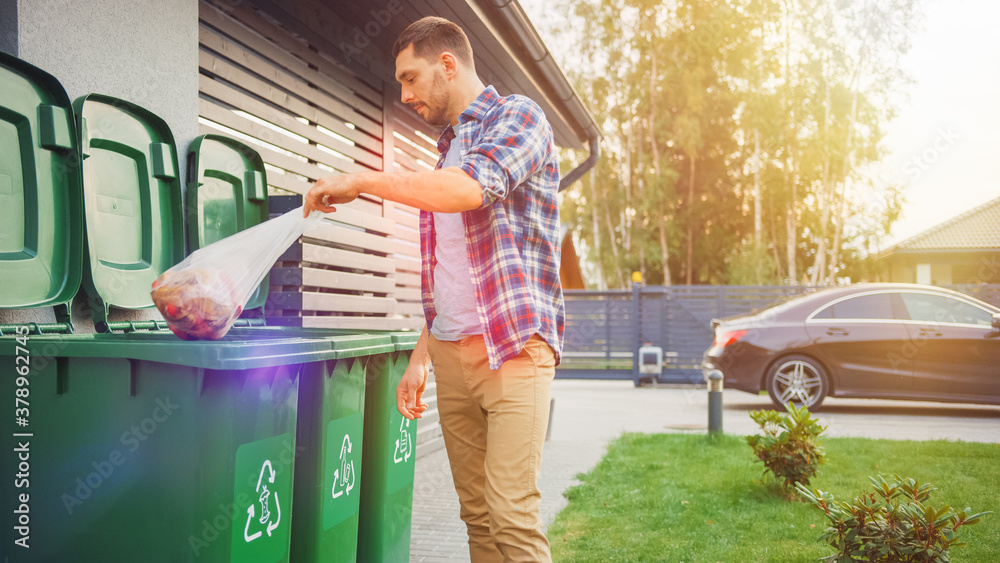 Caucasian Man is Throwing Away Two Plastic Bags of Trash next to His House. One Garbage Bag is Sorte