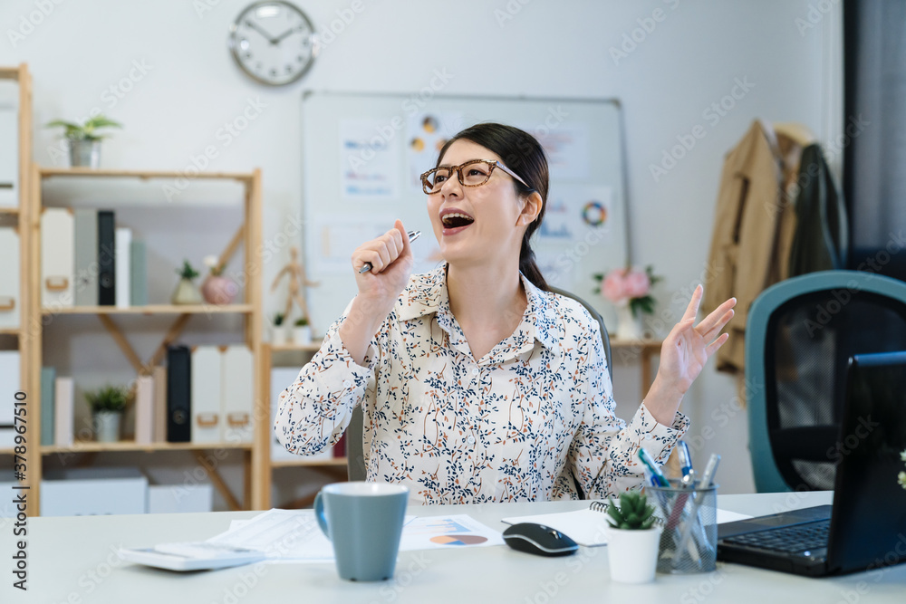 快乐迷人的女企业家，拿着服装设备坐在桌面上分析信息