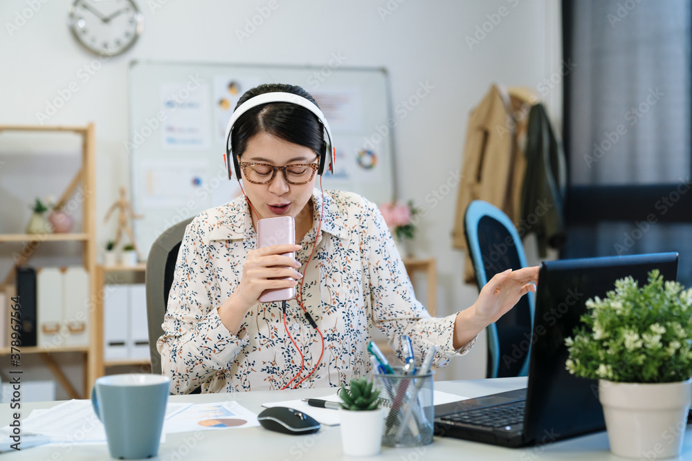 beautiful woman tailor singing and listening to music with headphones at workshop. Young asian femal