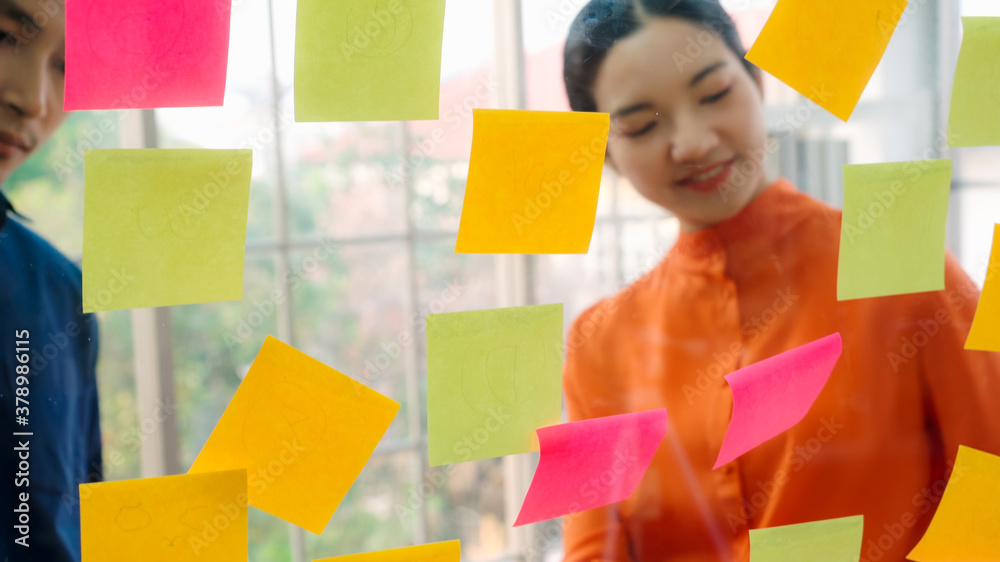 Business people work on project planning board in office and having conversation with coworker frien