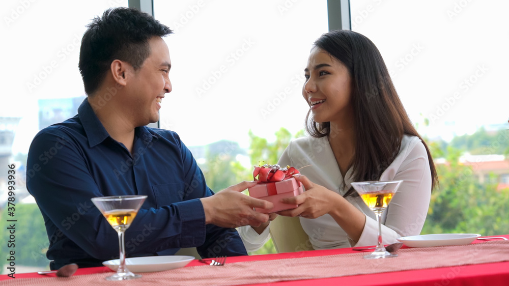 Romantic couple giving gift to lover at restaurant . Happy couple lifestyle .