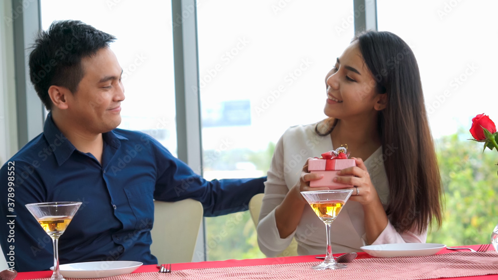 Romantic couple giving gift to lover at restaurant . Happy couple lifestyle .