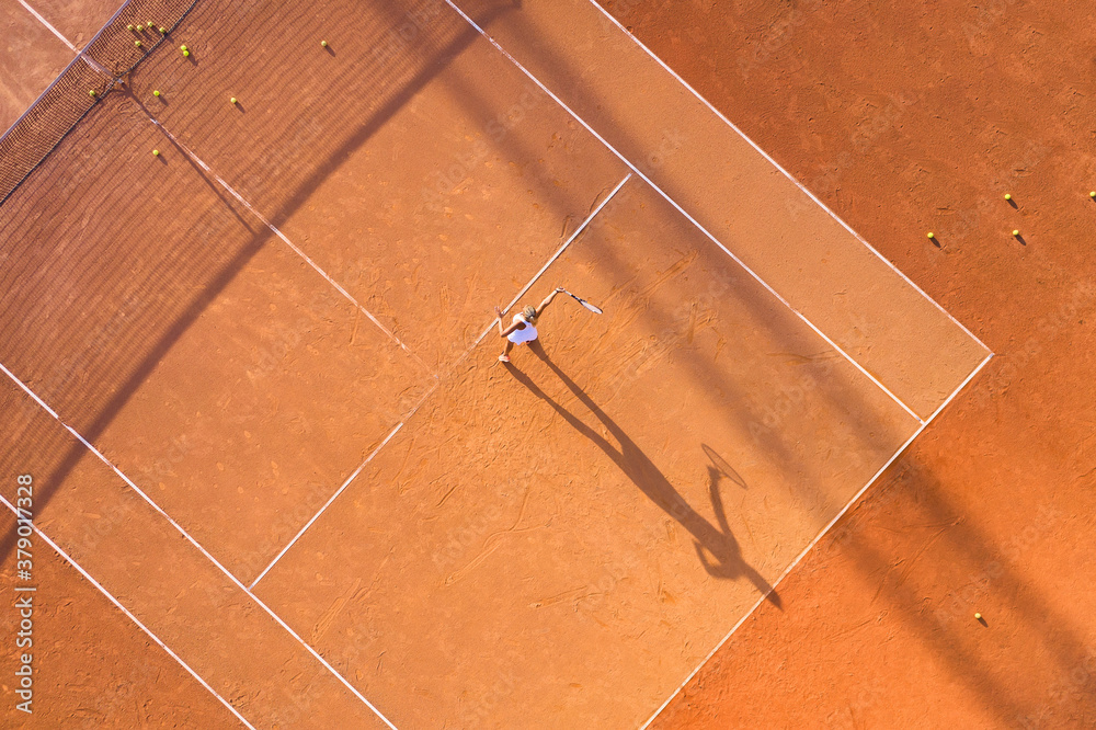 Healthy lifectyle. A young girl plays tennis on the court. The view from the air on the tennis playe