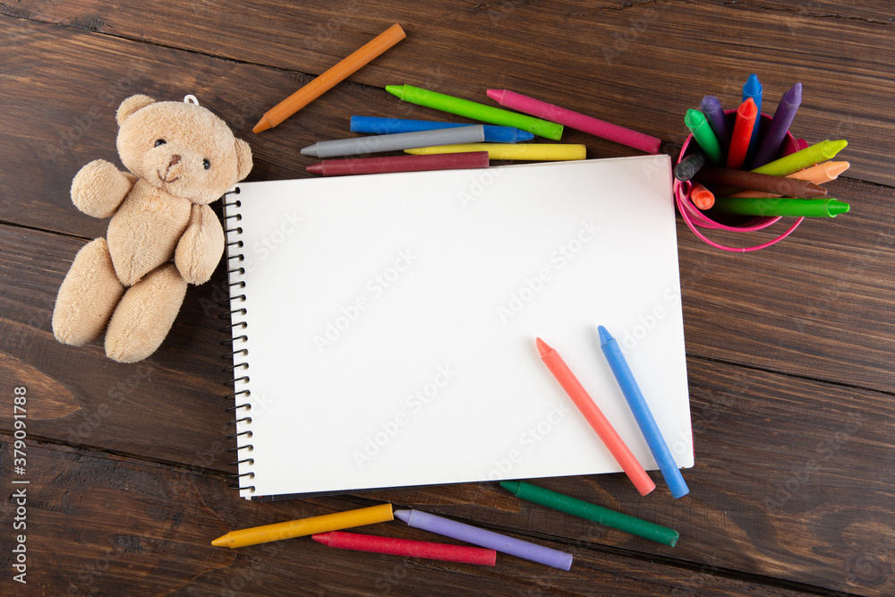 colored crayons and blank page on the wooden table