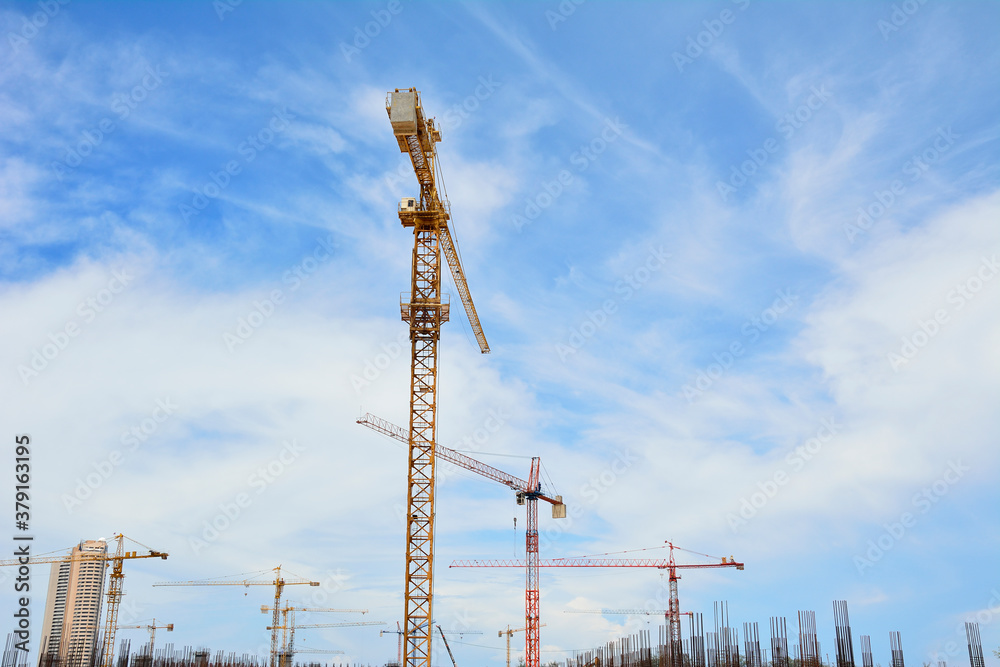 Cranes in industrial construction site with nice blue sky in background