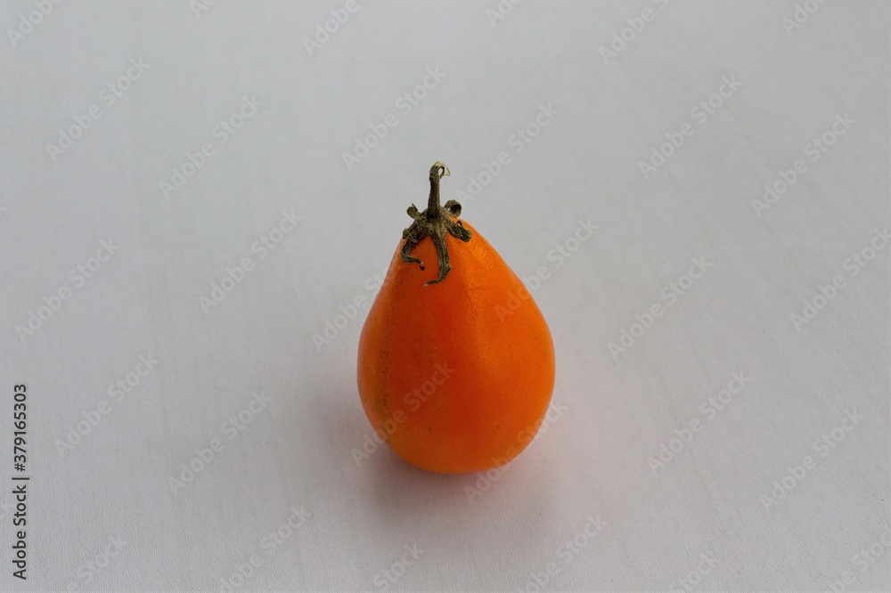 Large elongated yellow tomato on a light background, in daylight sunlight