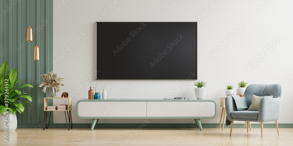 TV on cabinet in modern living room with armchair,lamp,table,flower and plant on white wall backgrou