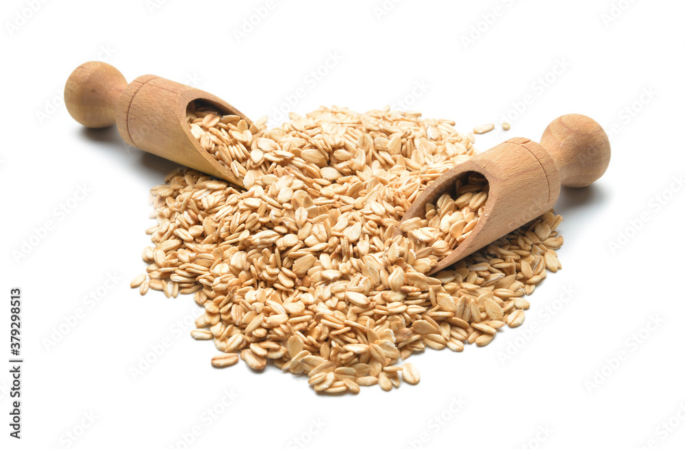 Raw oatmeal and scoops on white background