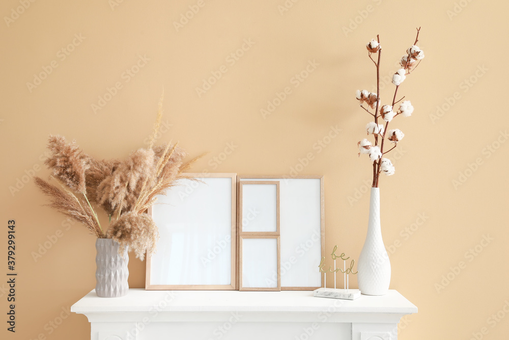 Fireplace with blank frames and decor near color wall