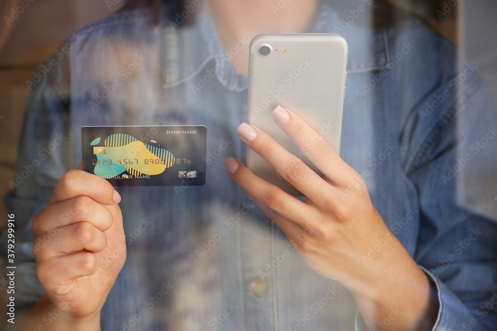 Young woman with credit card and mobile phone, closeup. Online shopping concept